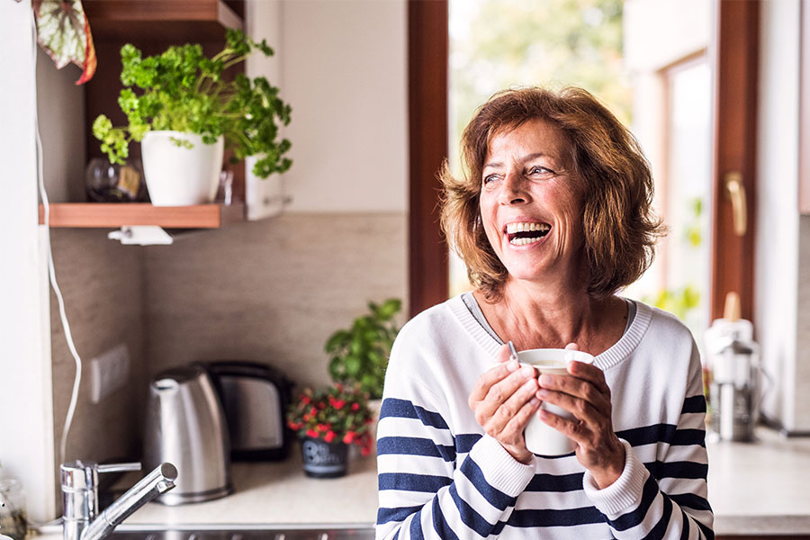 Laughing woman holding coffee while looking out the window