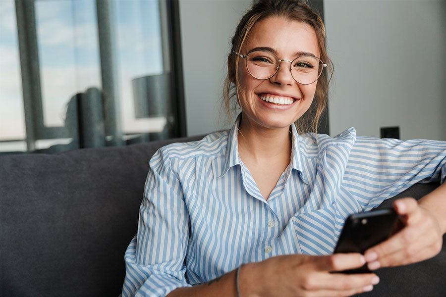 Smiling woman with eyeglasses holding her phone